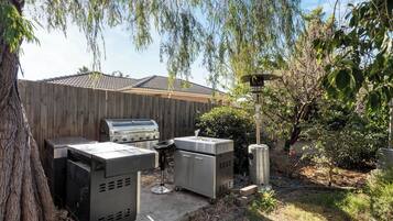 Ein Garten mit Grill, Wasserspiel und Holzzaun.