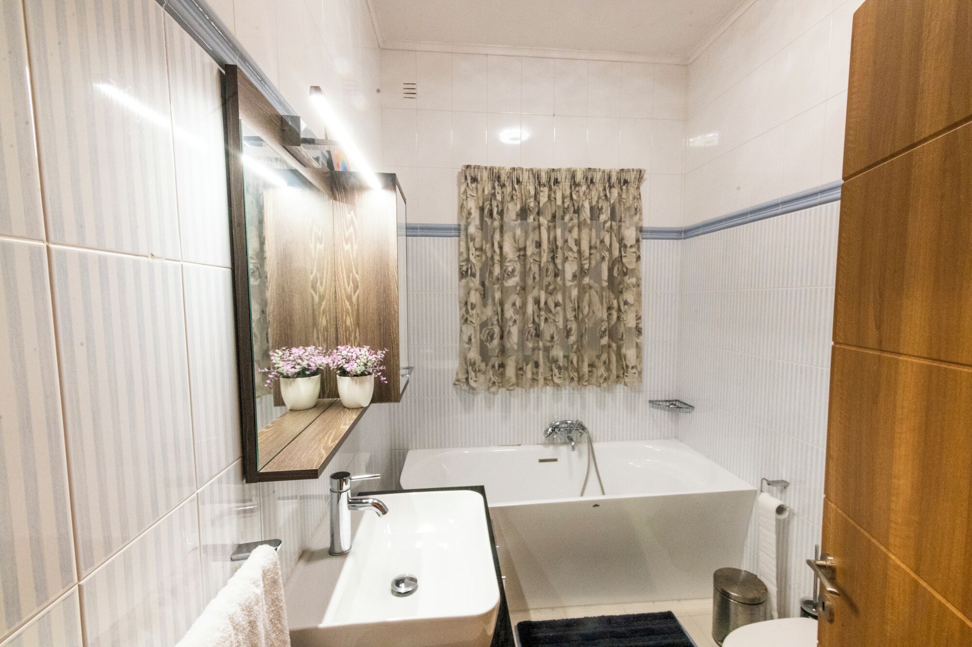Une salle de bain moderne avec une grande baignoire, un lavabo et un miroir.