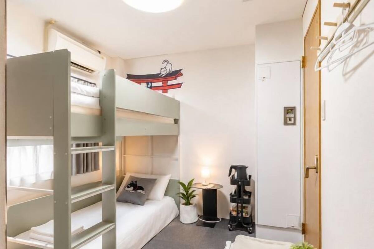 A bunk bed room with a desk, a small plant, and a wall-mounted heater.