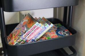 A black storage bin filled with colorful comic book magazines. - Oyasumi manga hotel (Osaka)