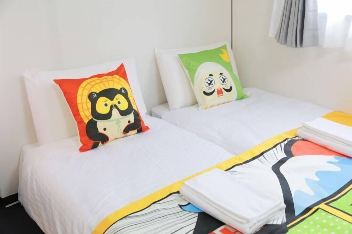 A hotel room with two beds, each with a colorful pillow.