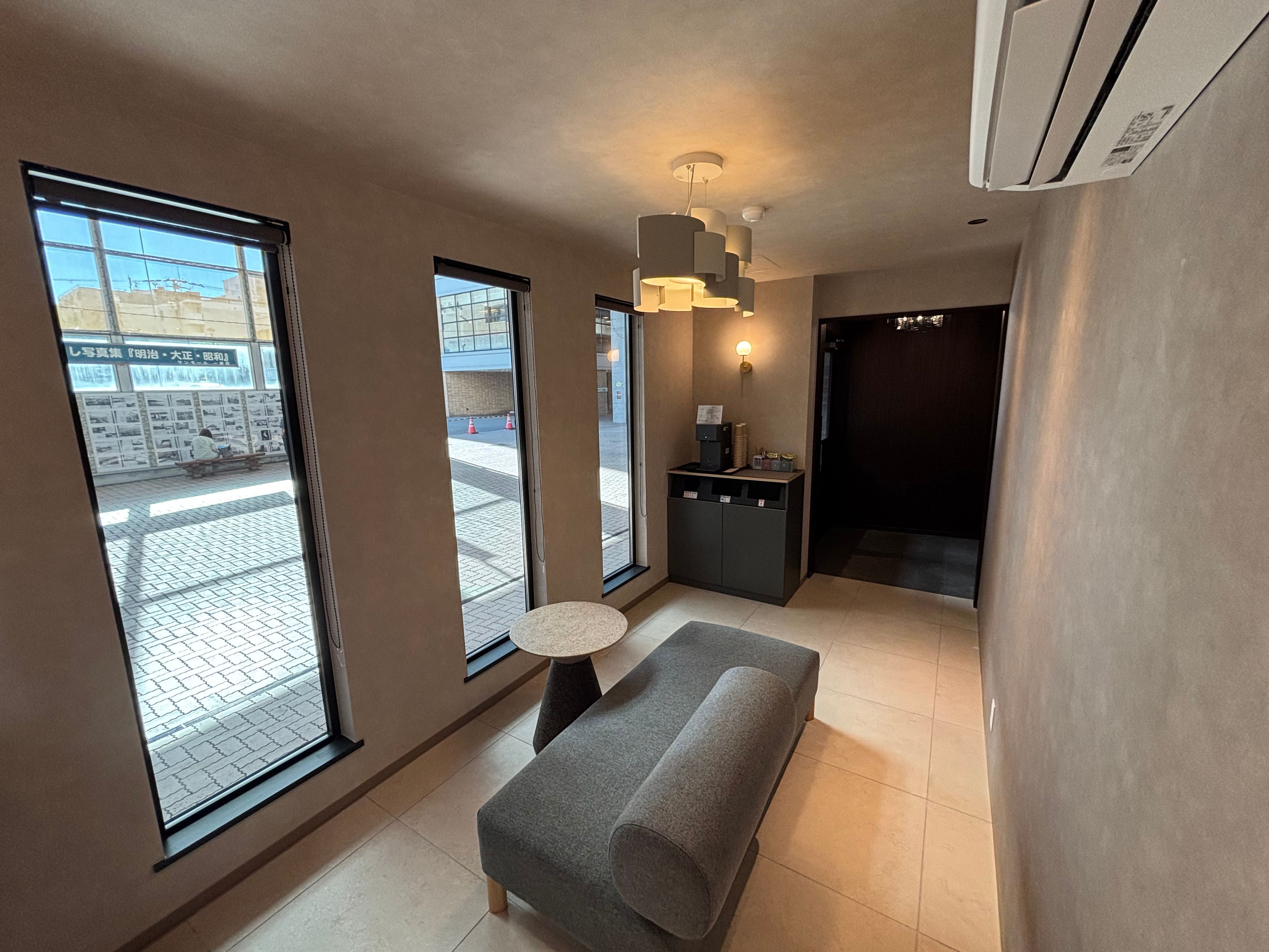 A modern interior with a sofa, a small round table, and a kitchenette area.
