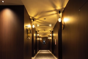 Passadís d'hotel amb parets de fusta, il·luminació empotrada i sòl amb moqueta.