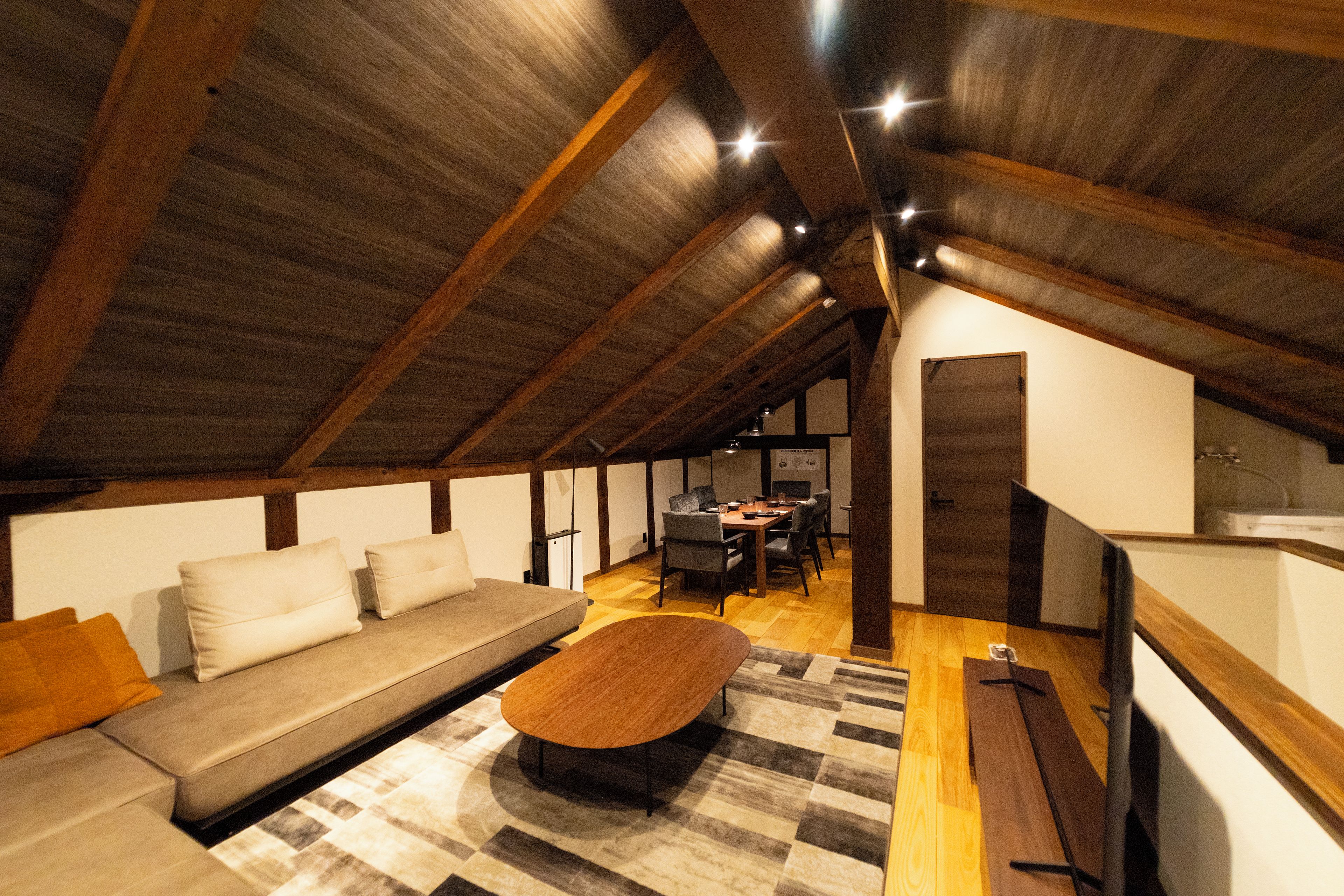An attic room with a sofa, a coffee table, and a dining area.