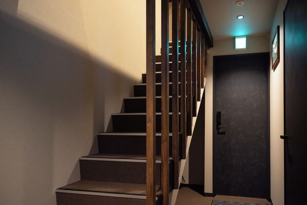 A staircase with wooden railings and carpeted steps leading to a dark door.