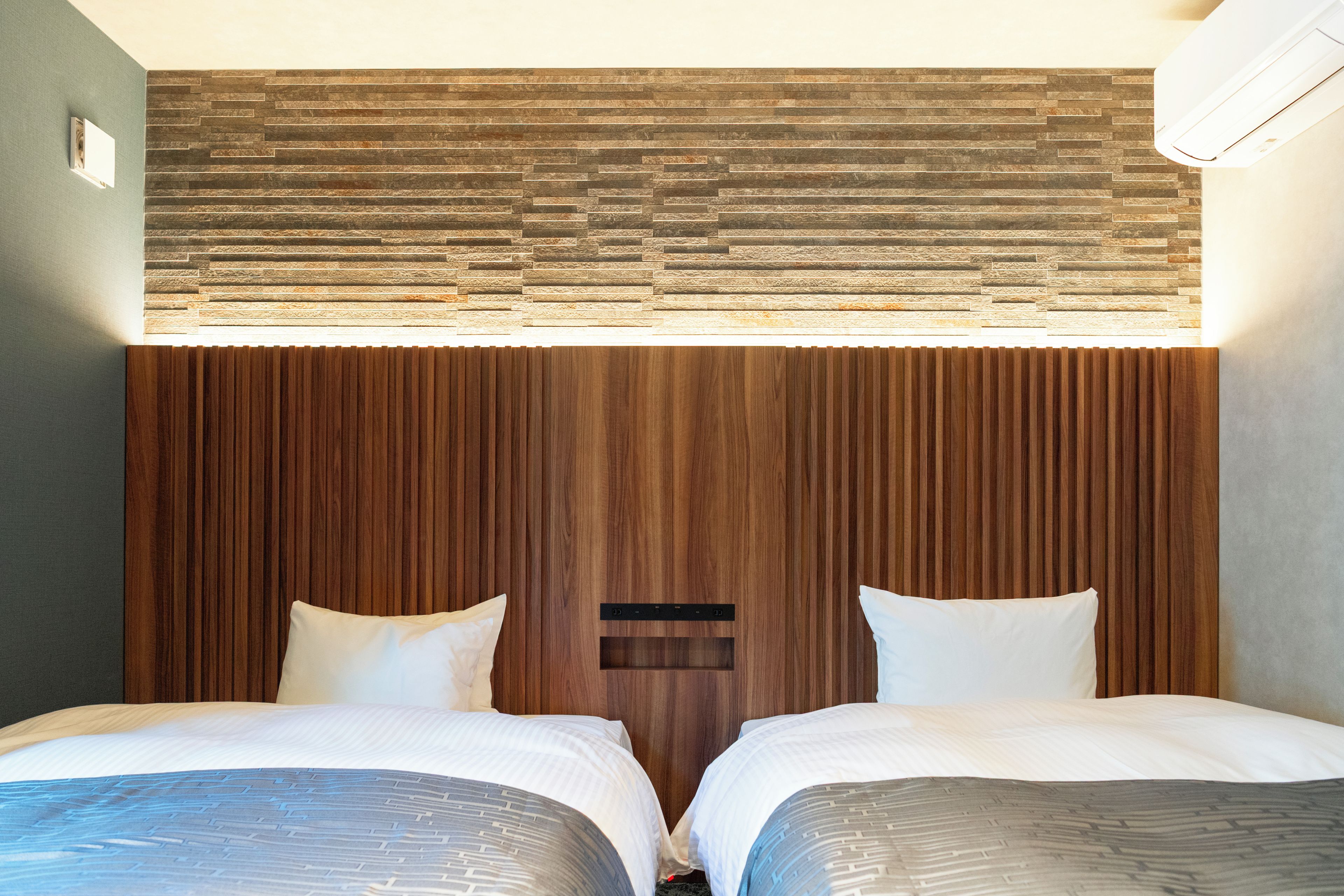 A hotel room with two beds, a wooden headboard, and a small window.
