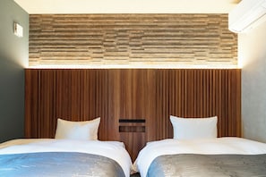 Una habitación de hotel con dos camas, cabecero de madera y un ventanal pequeño.