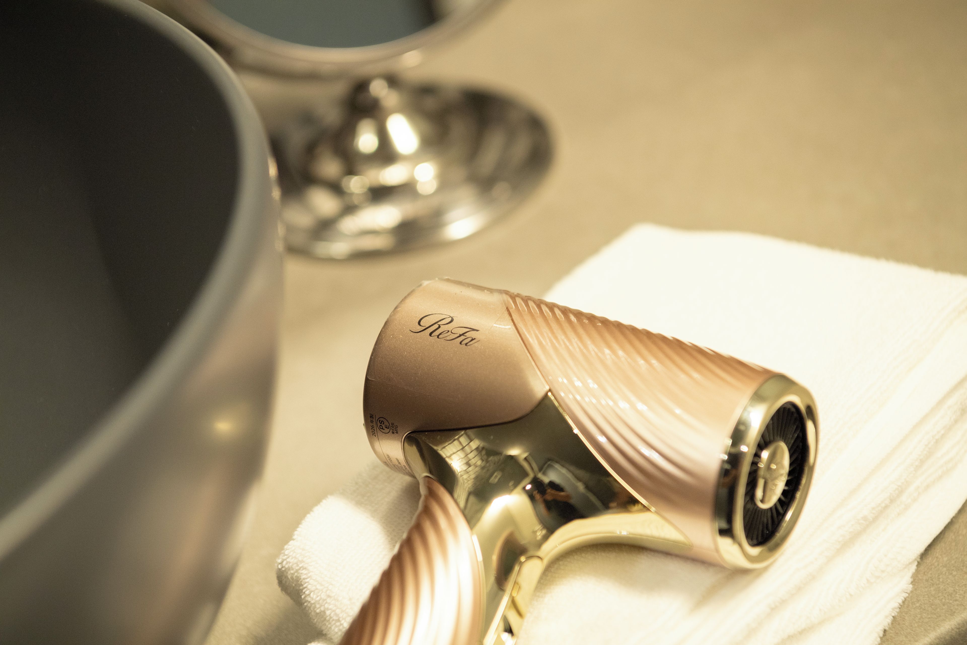 A metallic object with a reflective surface, possibly a part of a piece of furniture or equipment, resting on a white cloth.