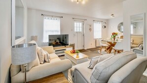 A modern living room with a sofa, coffee table, and a dining area with chairs and a table. - Seaside Luxury Cottage *Aldeburgh* (Aldeburgh)