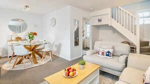 A modern living room with a dining area, a staircase, and a view of the adjacent room. - Seaside Luxury Cottage *Aldeburgh* (Aldeburgh)