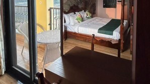 Makuuhuoneessa on sänky, tuoli, pöytä ja parveke, jolta on näkymä.