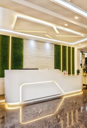 A modern reception desk with a white finish and integrated lighting. - The Marella Suites (Bengaluru)