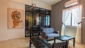 A modern living room with a sofa, a bench, a table, and a painting of a tiger. - Mac Inn 94 (George Town)