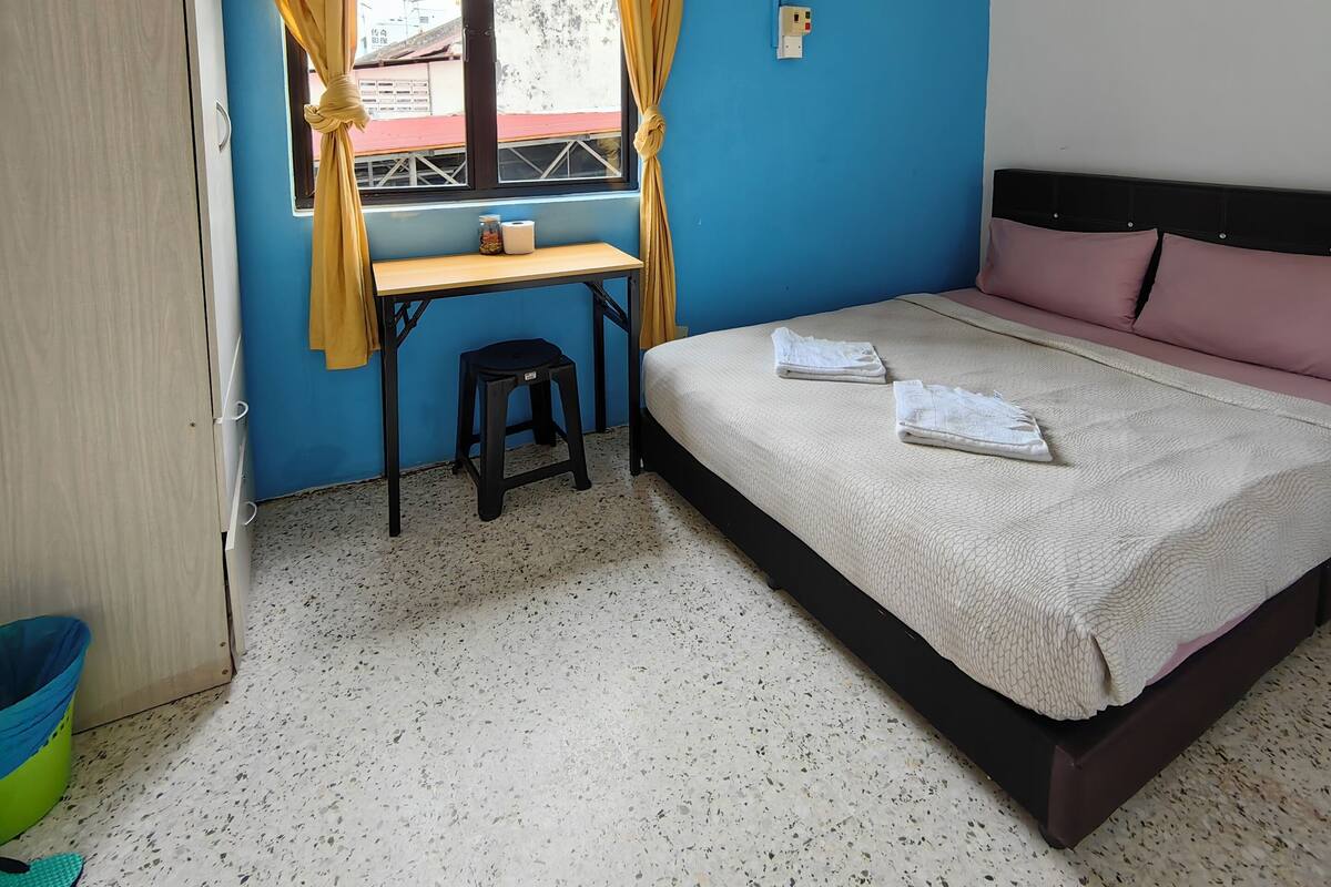 A room with a bed, a desk, a chair, a ceiling fan, and an air conditioning unit.