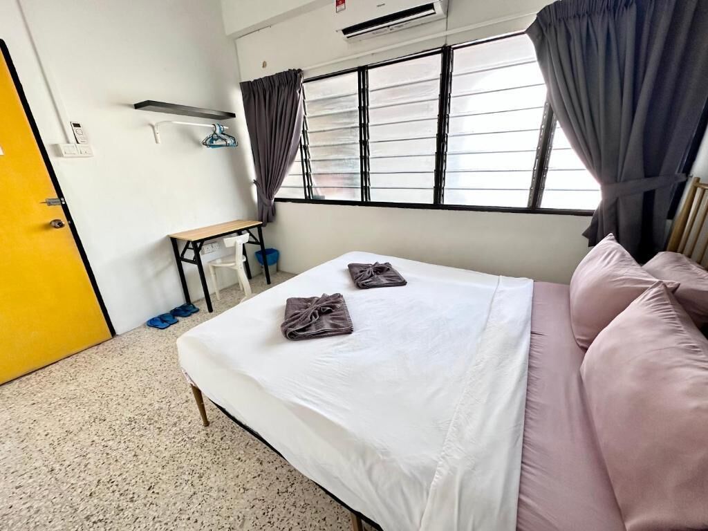 A hotel room with a bed, a desk, and a window with curtains.