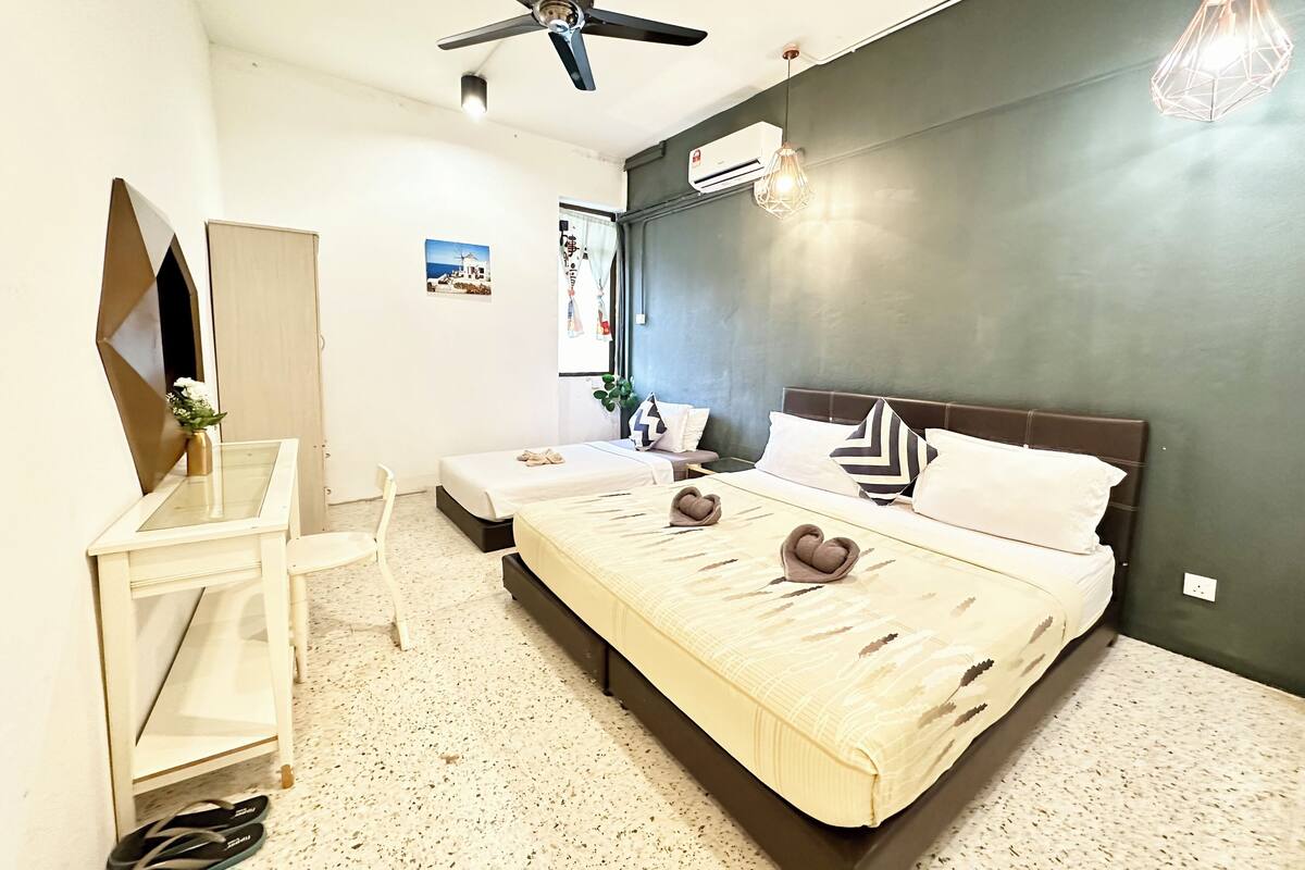 A modern hotel room with a large bed, a desk, a chair, and a ceiling fan.