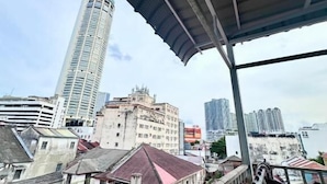 A view from a covered balcony overlooking a cityscape with a mix of modern and older buildings, including a tall skyscraper. - Mac Inn 94 (George Town)