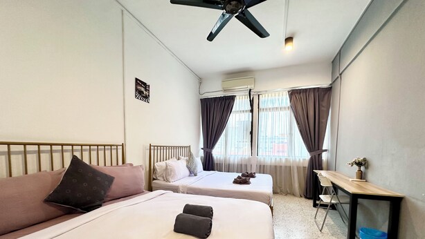 A hotel room with two beds, a desk, a chair, a ceiling fan, and a window with curtains. - Mac Inn 94 (George Town)