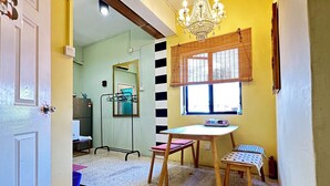 A room with a dining table, chairs, a chandelier, and a window with blinds. - Mac Inn 94 (George Town)