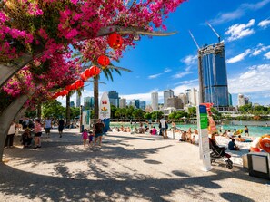 A beachside promenade with a view of a modern city skyline, including a tall building under construction.