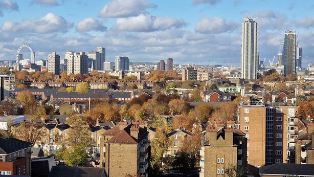 A cityscape with a mix of residential and commercial buildings, including high-rise structures and a prominent Ferris wheel in the background. - Charming 2-bedroom Apartment in Central London (London)
