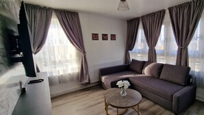 A living room with a sofa, a coffee table with flowers, and curtains on the windows. - Charming 2-bedroom Apartment in Central London (London)