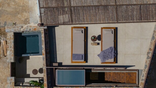 Vue aérienne d’une chambre d’hôtel moderne à la façade en pierre, comprenant deux chambres avec salle de bain attenante, une petite piscine et un coin repas.