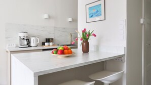 A modern kitchen with a white countertop, a coffee maker, a sink, and a vase with flowers. - Stylish Studio in the Heart of Kallio (Helsinki)