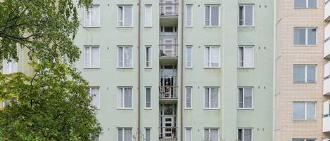 Un immeuble résidentiel à plusieurs étages, doté d’un escalier central et entouré de verdure et d’arbres.