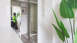 A modern interior with a glass door leading to a room, a potted plant, and a framed picture on the wall. - Stylish Studio in the Heart of Kallio (Helsinki)