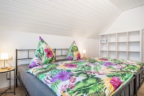Une pièce comprenant un lit, deux tables de chevet, une étagère fixée au mur et un plafond en pente.