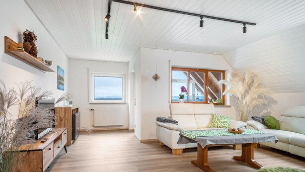 Un salón moderno con sofá, una mesa de centro de madera y vistas al exterior.