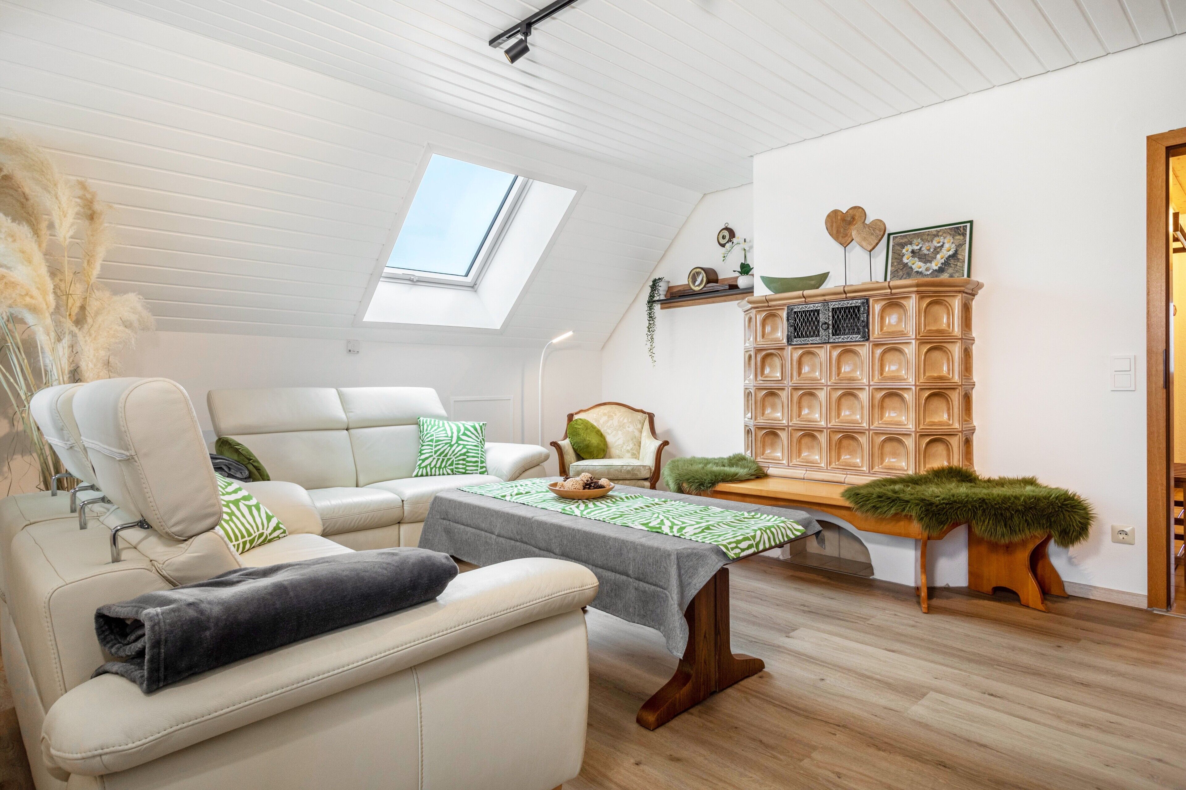 A modern living room with a high ceiling, a skylight, a sofa, a coffee table, and a decorative wooden cabinet.