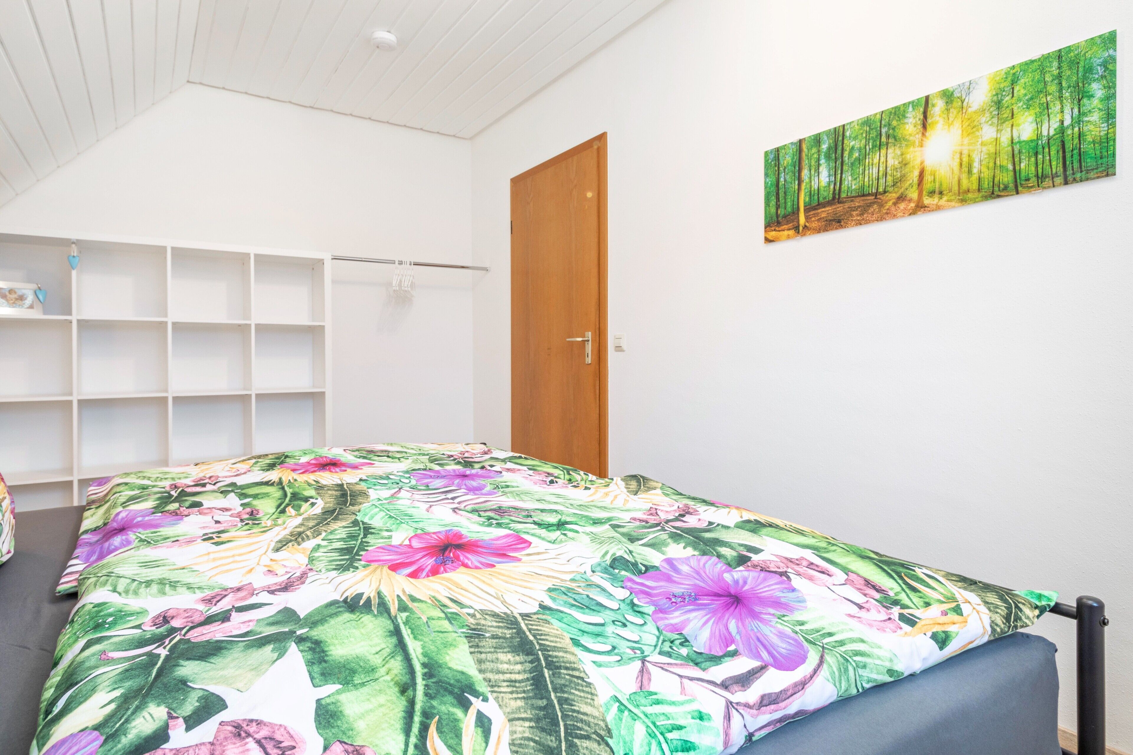 A bedroom with a bed, a wardrobe, and a painting on the wall.