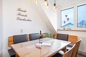 Un espace repas comprenant une table, des chaises, une bouteille de vin et un menu.
