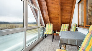 Una habitación con techo inclinado, ventanas amplias y sillones de estampado escocés.