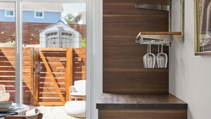 A modern kitchen with a wooden cabinet, a built-in wine rack, and a sliding glass door leading to a patio. - Urban Oasis Loft Pet Yard Parking (Austin)