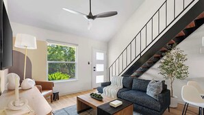A modern living room with a sofa, coffee table, and a staircase. - Urban Oasis Loft Pet Yard Parking (Austin)