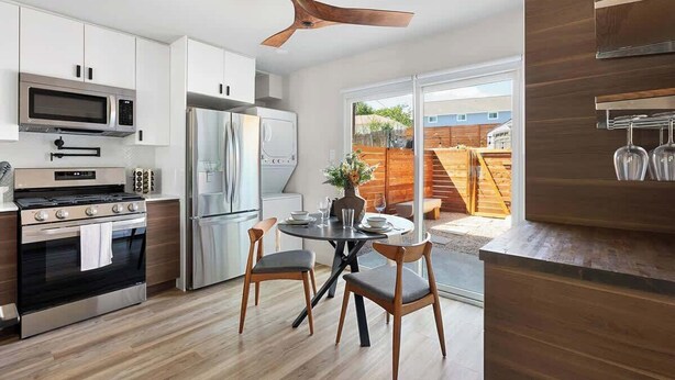 A modern kitchen with white cabinets, stainless steel appliances, and a dining area with two chairs and a table. - Urban Oasis Loft Pet Yard Parking (Austin)