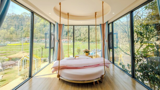 A modern bedroom with a swing bed, large windows, and a view of a green landscape. - Harbor Diary Homestay (Xuancheng)
