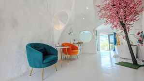 A modern interior with teal and orange chairs, a white wall, and a large artificial tree. - Harbor Diary Homestay (Xuancheng)