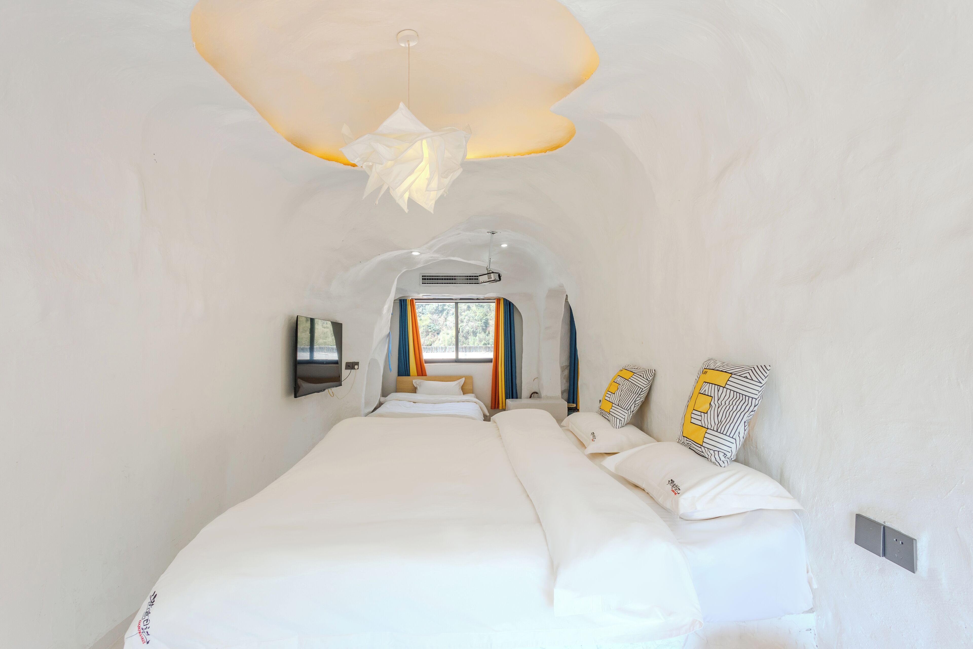 Habitación de hotel moderna con una cama grande, un diseño de techo original y vistas al exterior.