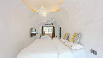 Habitación de hotel moderna con una cama grande, un diseño de techo original y vistas al exterior.