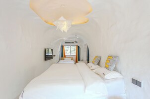 Habitación de hotel moderna con una cama grande, un diseño de techo original y vistas al exterior.