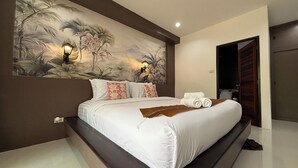 A modern hotel room with a large bed, a wall mural, and a wooden door. - Echo Samadhi (Ko Lanta)