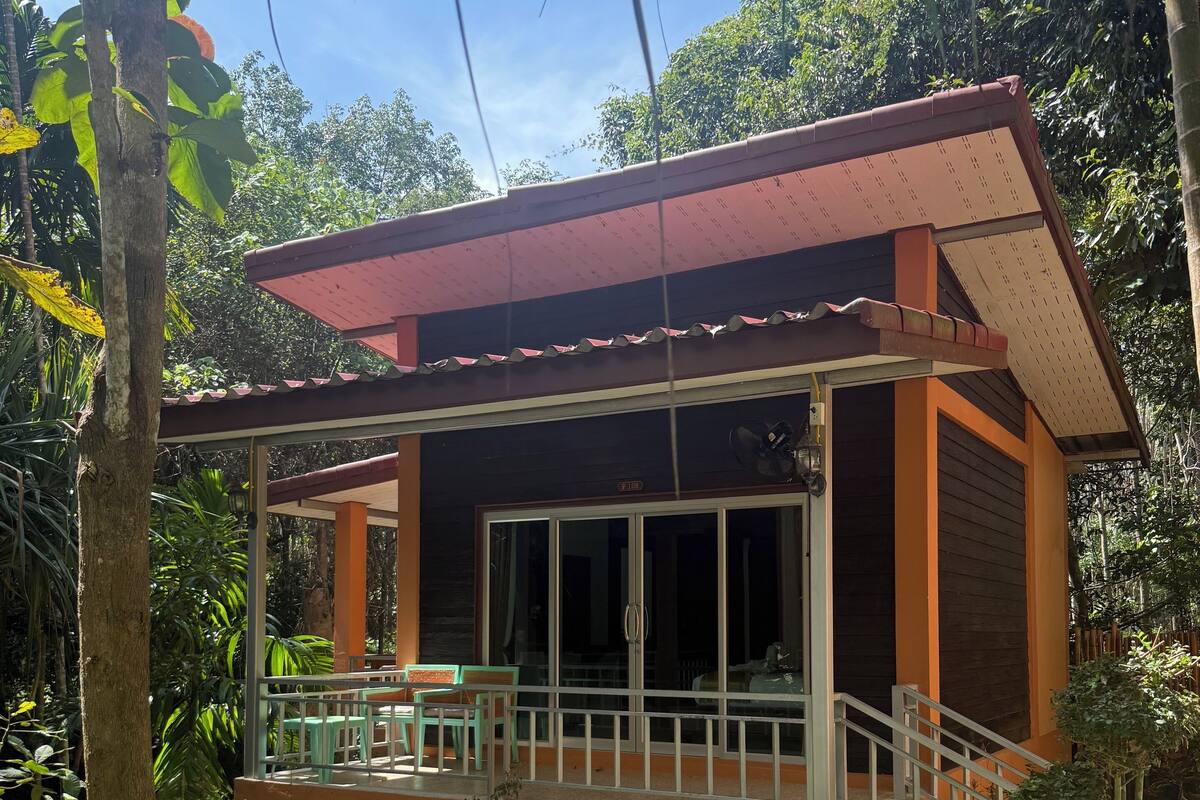 A two-story building with a balcony, surrounded by greenery.