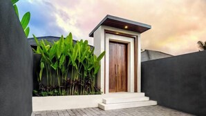 A modern house with a wooden door, a small porch, and a brick pathway. - Villa Samaddhi by BaliSuperHost (Bali)
