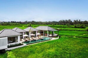 A resort with multiple overwater bungalows, a swimming pool, and lush green fields. - Villa Samaddhi by BaliSuperHost (Bali)