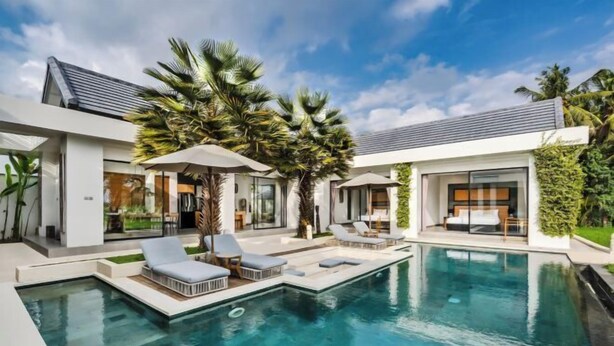 A modern poolside area with lounge chairs, a swimming pool, and a house with large windows and a covered patio. - Villa Lina by BaliSuperHost (Bali)