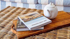 A modern living room with a striped sofa, a wicker coffee table, and a white teapot. - Marmoris Bay of Fires - A laid back coastal retreat with shimmering ocean views (Binalong Bay)